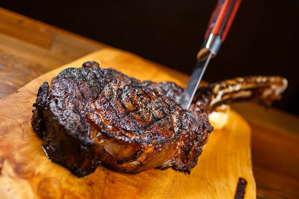 A sliced steak on a plate as a knife cuts through it